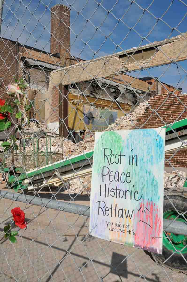 Handmade sign decorates the construction fence at the demolition site.